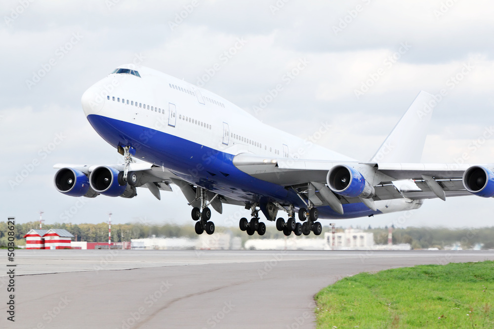Large blue and white passenger airplane takes off at airport. Large blue and white passenger airplane takes off at airport.