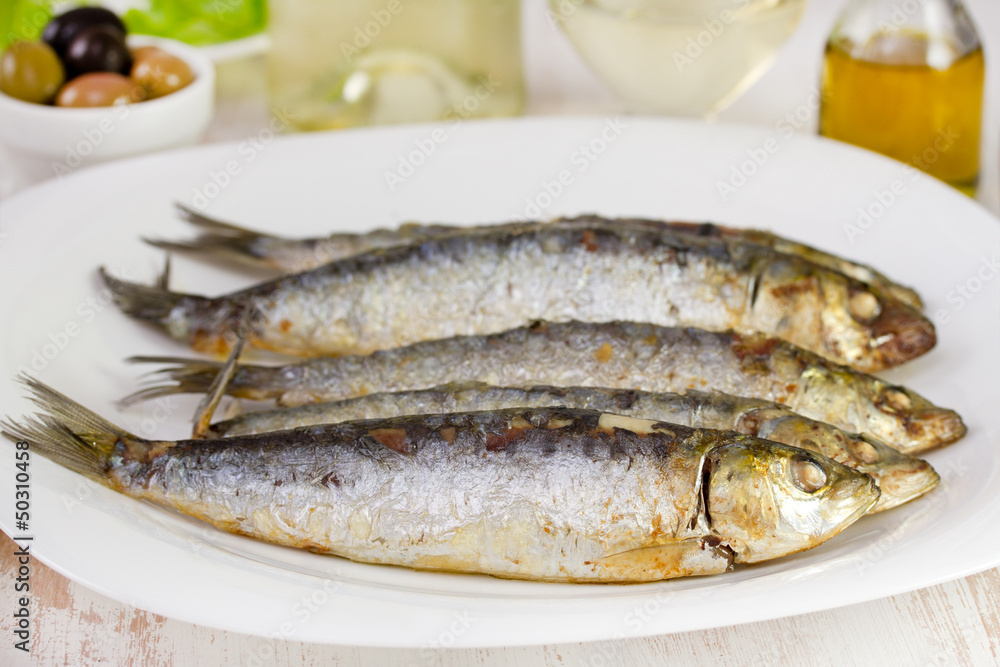 fried sardines on the plate with glass of wine fried sardines on the plate with glass of wine