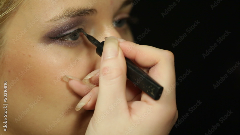 Detail of a young woman applying eye liner makeup Detail of a young woman applying eye liner makeup