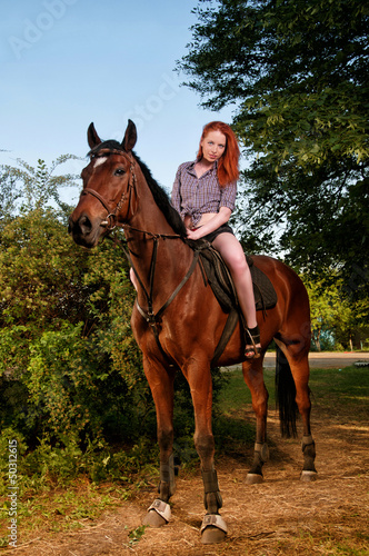 woman with red hair sitting on a horse © Artem Merzlenko