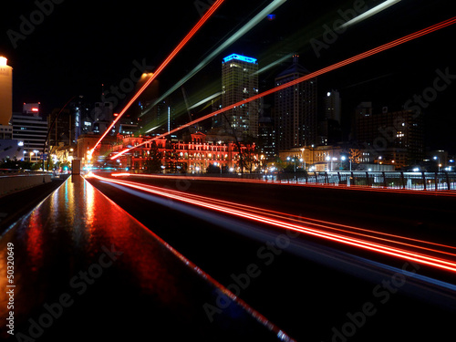 Motion blur effect caused by red taillights of fast driving bus creating light trails at night Brisbane city center in Australia 