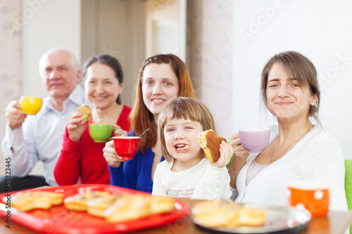 Happy family drinks tea with cakes