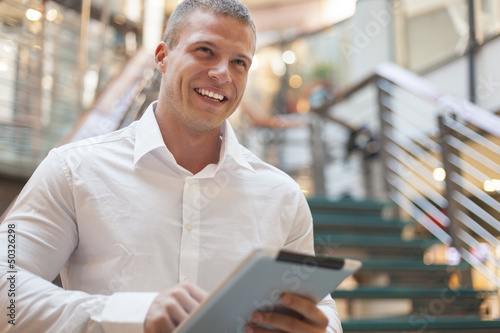 Smiling Man with tablet computer in modern business building