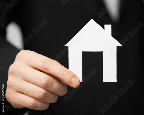 man in suit holding paper house