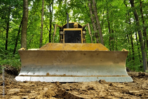 Bulldozer standing in forest for deforestation