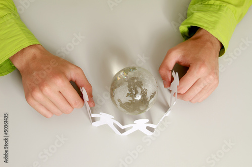 Male hands holding paper people around a glass globe