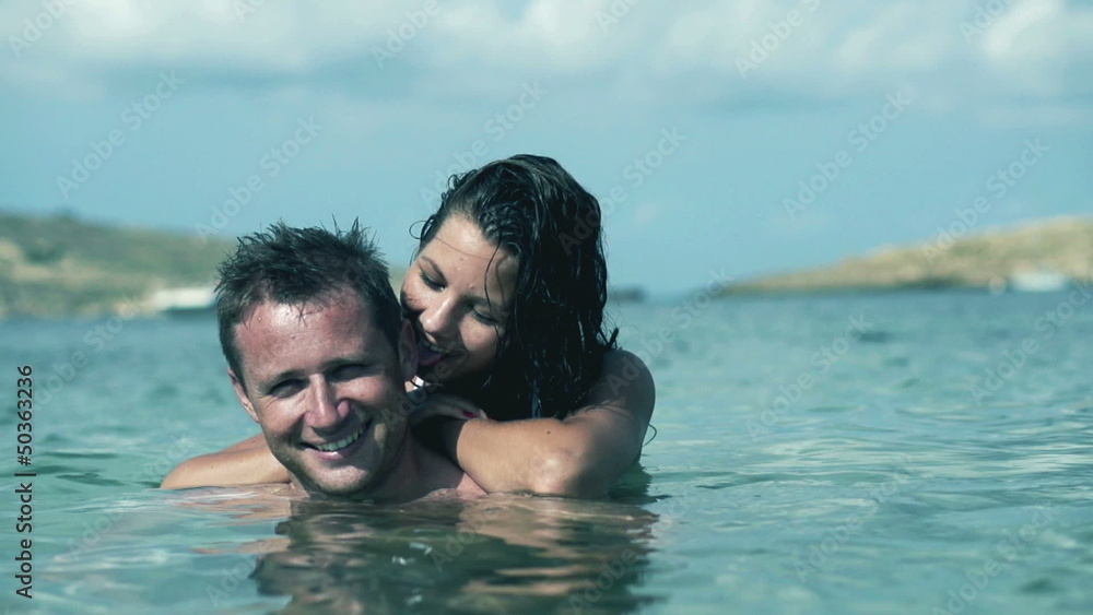 Happy couple standing in te sea and smiling, slow motion shot at Happy couple standing in te sea and smiling, slow motion shot at