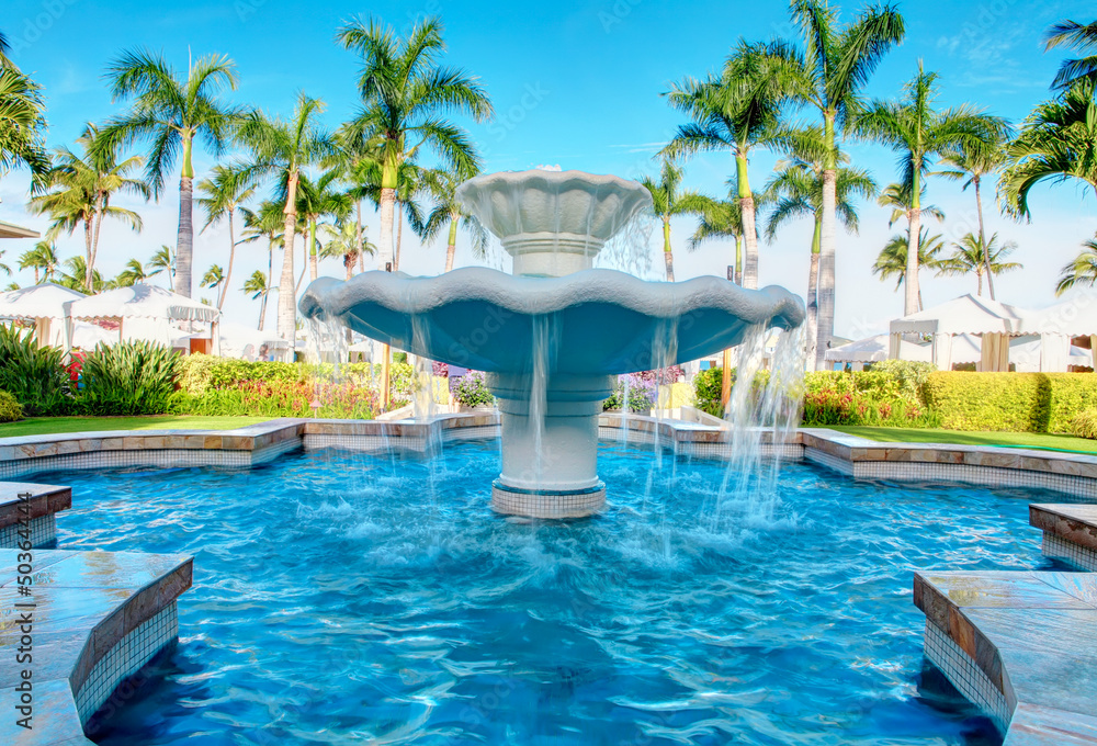 Luxury water fountain in tropial resort with palm trees.