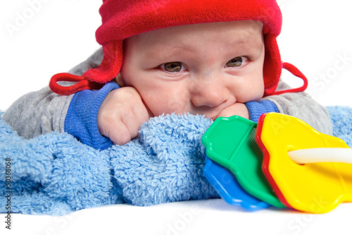 baby lying on his stomach with red cap