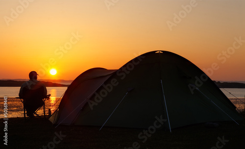 sunsets behind camper and tent
