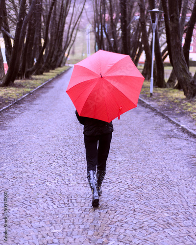 Foto Girl with red umbrella walking away