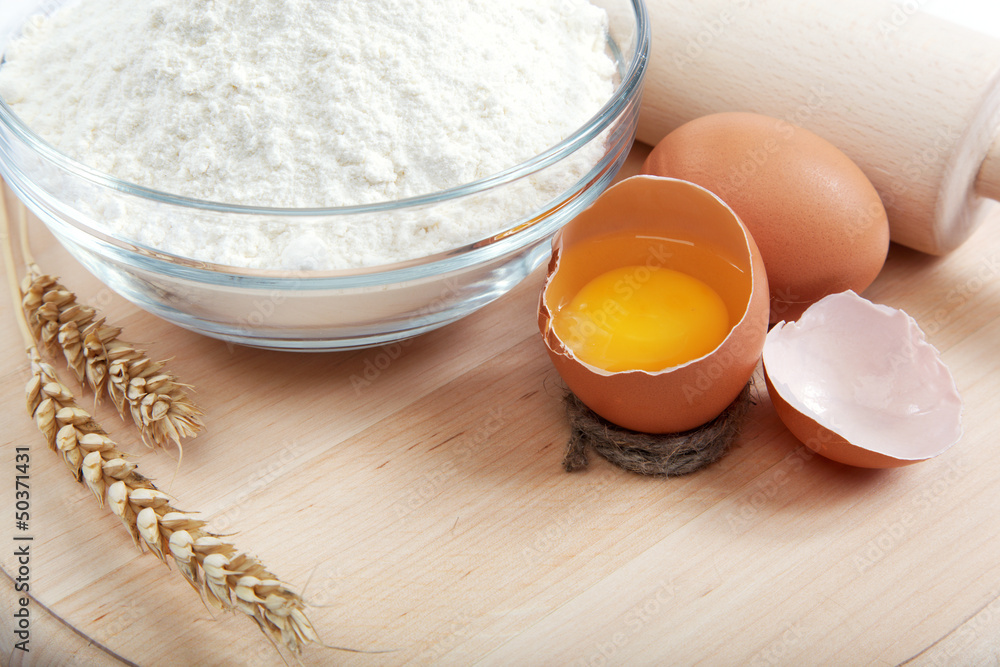 Flour with raw eggs for making dough on the wooden board. Flour with raw eggs for making dough on the wooden board.