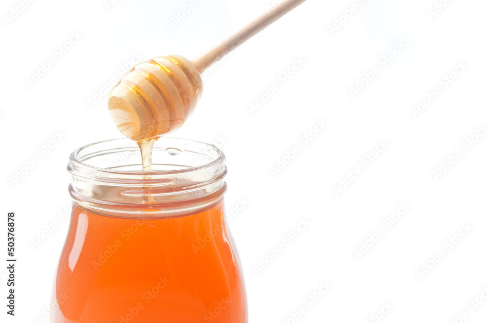 Jar of honey with wooden drizzler isolated on white background Jar of honey with wooden drizzler isolated on white background
