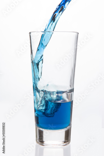 Glass being filled with blue liquid