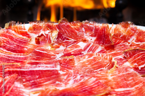 plate of Spanish jamon iberico sliced with a fireplace as back