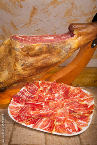 Leg and plate of Spanish jamon iberico (ham) in a cave