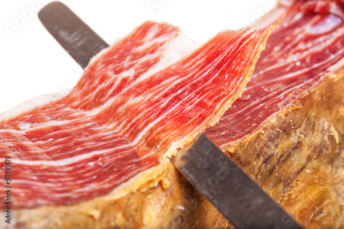Slicing Spanish jamon iberico (ham) on white background