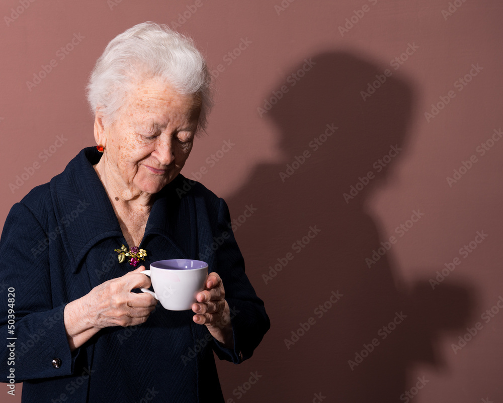 Old woman enjoying coffee or tea cup over brown background Old woman enjoying coffee or tea cup over brown background