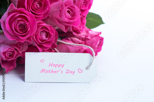 Bouquet of beautiful roses with happy mothers day card on a tabl