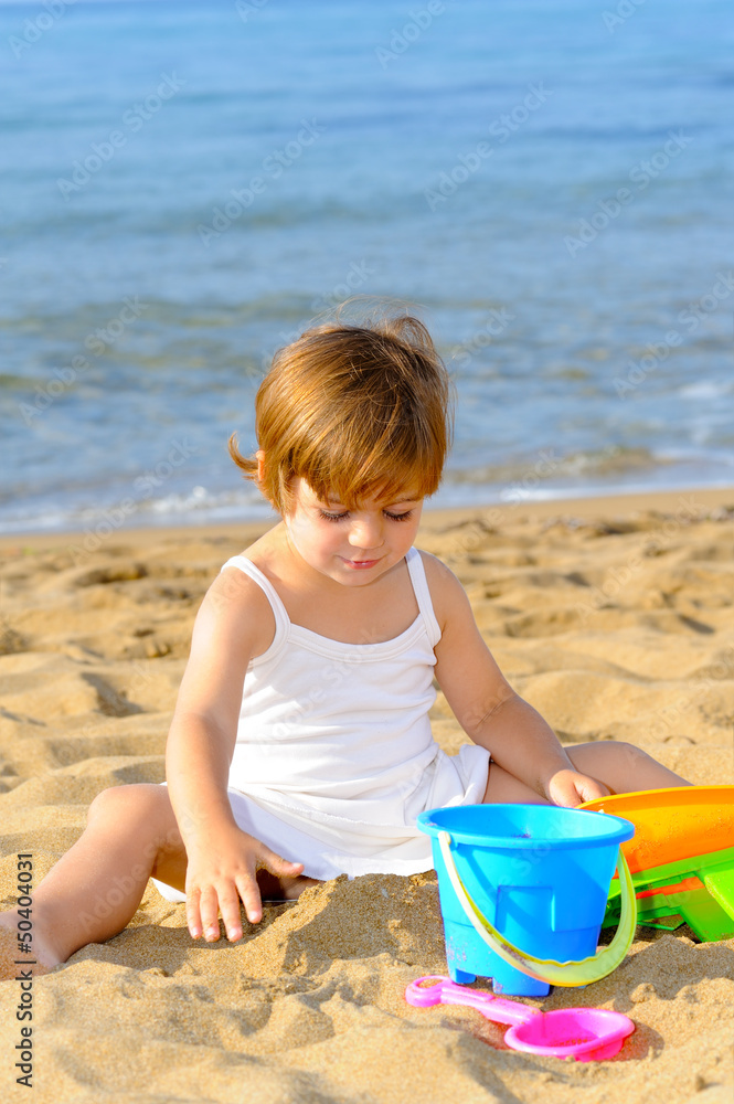 Happy toddler girl playing with her toys at beach Happy toddler girl playing with her toys at beach