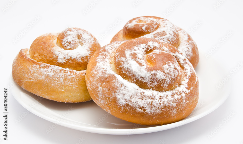 Group of delicious cinnamon rolls icing sugar on plate isolated