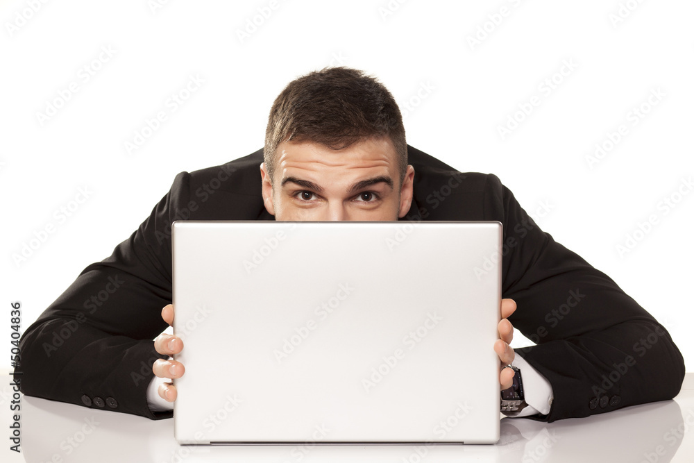 young and funny businessman hiding behind his laptop young and funny businessman hiding behind his laptop