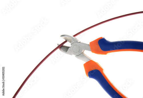 Foto Metal nippers is cutting red cable on white background