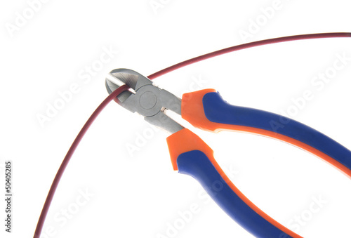 Metal nippers is cutting red cable on white background photo