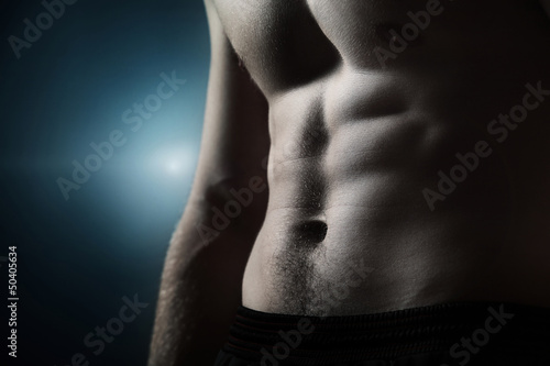 Muscular naked man on dark background