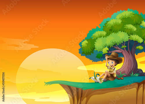 A boy sitting near a big tree