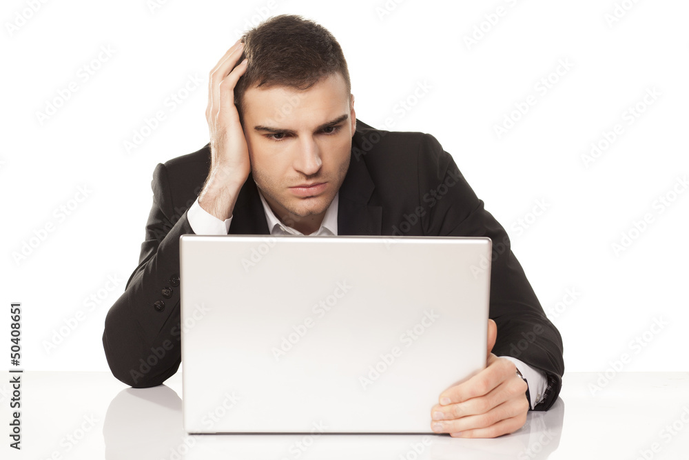 young businessman staring helplessly at his laptop young businessman staring helplessly at his laptop