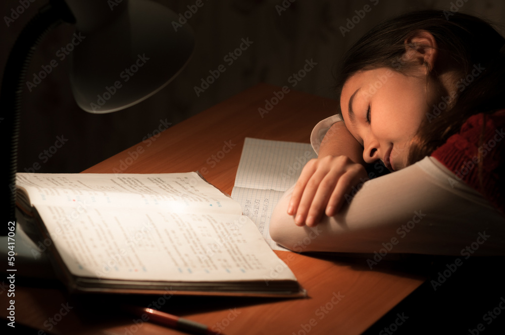 Girl asleep at a table doing homework Girl asleep at a table doing homework