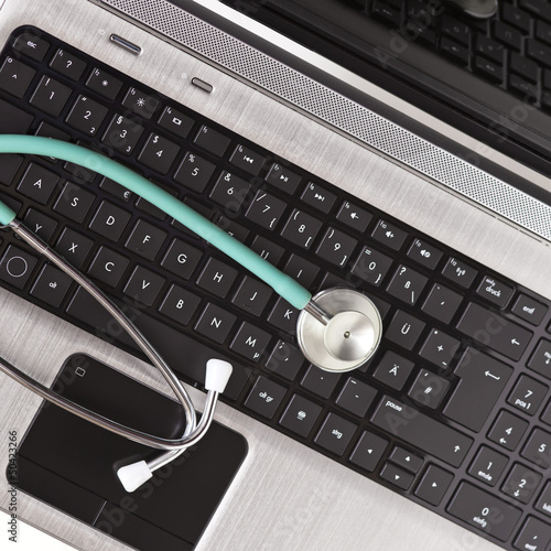 Ein Stethoskop liegt auf der Tastatur des Laptops