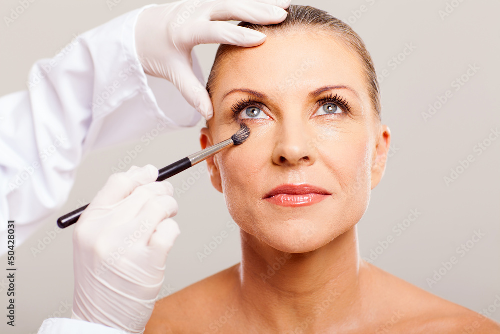 beautician putting makeup on mid age woman beautician putting makeup on mid age woman