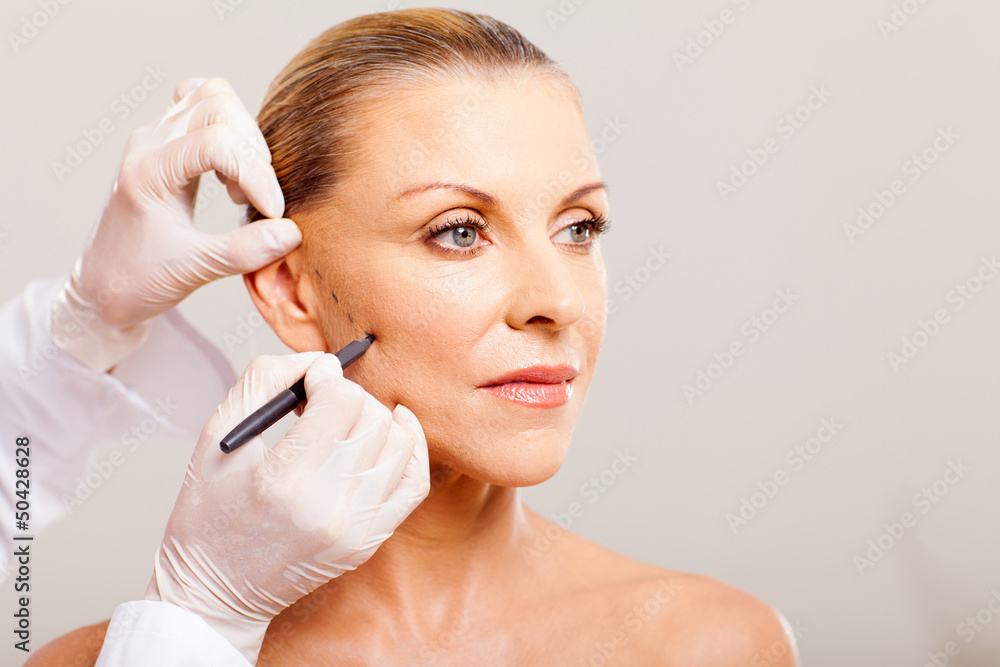 cosmetic surgeon drawing on senior woman face