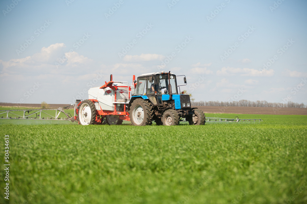 Tractor spraying a green field on a farm Tractor spraying a green field on a farm