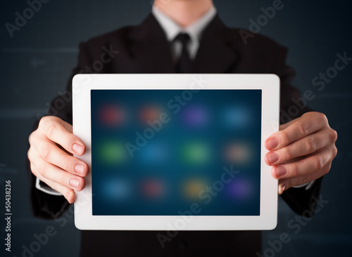 Wallpaper Mural Businessman holding a white modern tablet with blurry apps Torontodigital.ca