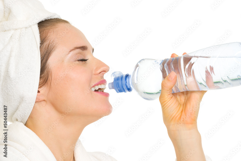 Young woman in bathrobe drinking from bottle with water Young woman in bathrobe drinking from bottle with water