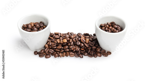 heap of coffee beans with two cups