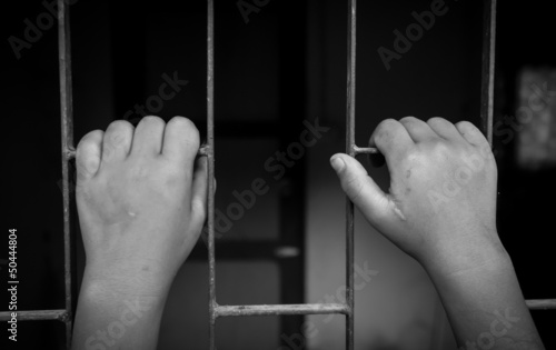 hands of a girl are grabbing steel cage