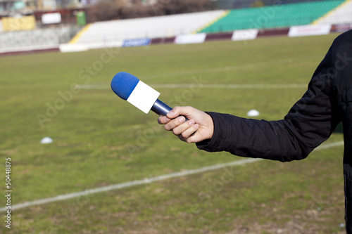 hand hold microphone for interview during a football mach