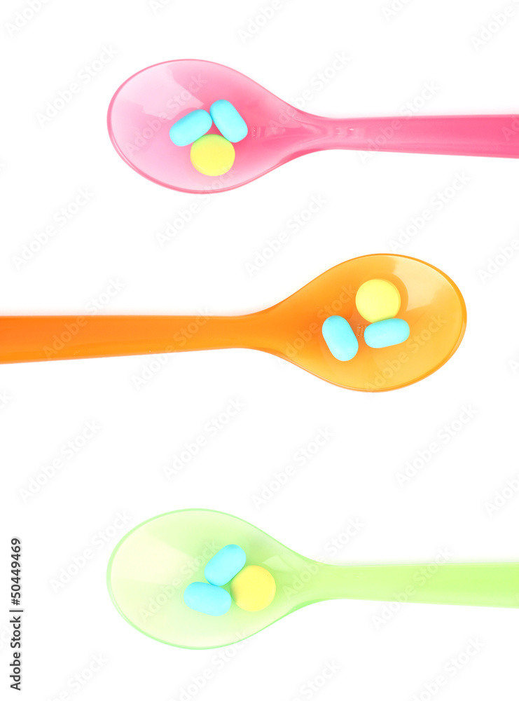 Plastic spoons with color pills, isolated on white Plastic spoons with color pills, isolated on white