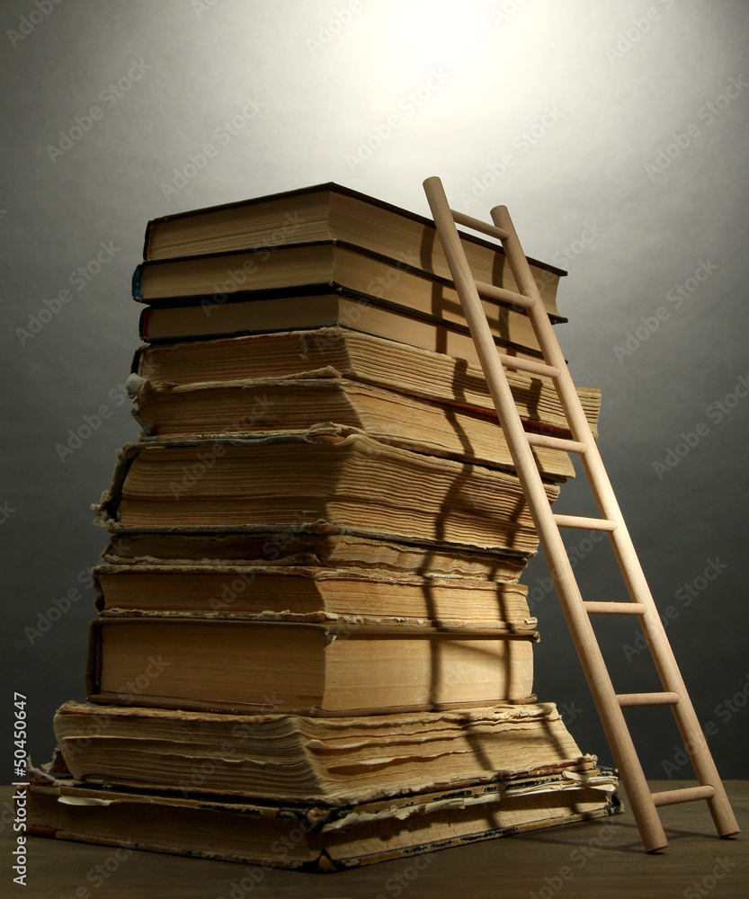 Old books and wooden ladder, on grey background Old books and wooden ladder, on grey background