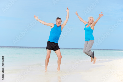 Senior Couple Jumping On Beautiful Beach