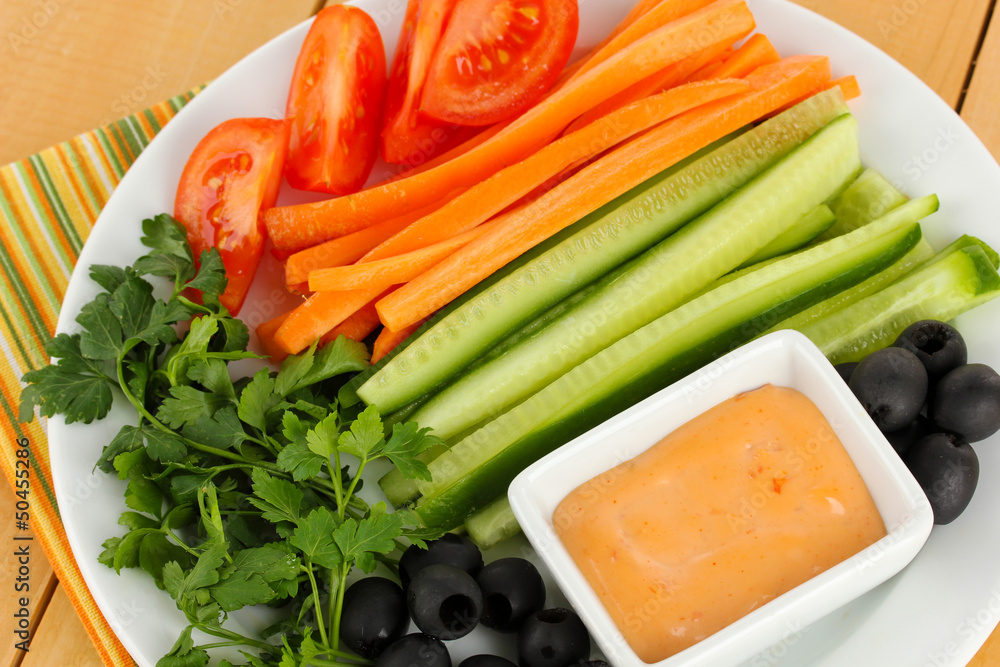 Assorted raw vegetables sticks in plate on wooden table close Assorted raw vegetables sticks in plate on wooden table close