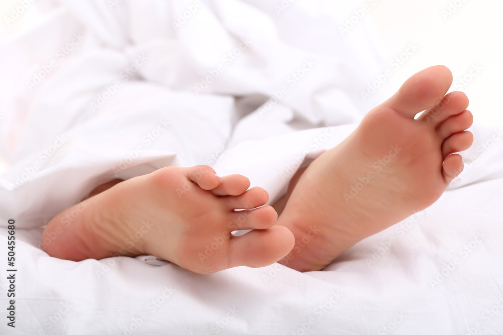 Beautiful feet of a young woman lying in bed close up Beautiful feet of a young woman lying in bed close up