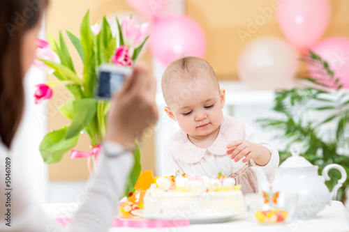 Mother making photos of daughter with birthday cake