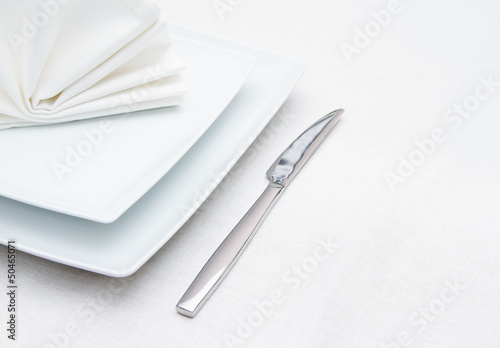 White place setting with knife and folded white napkin