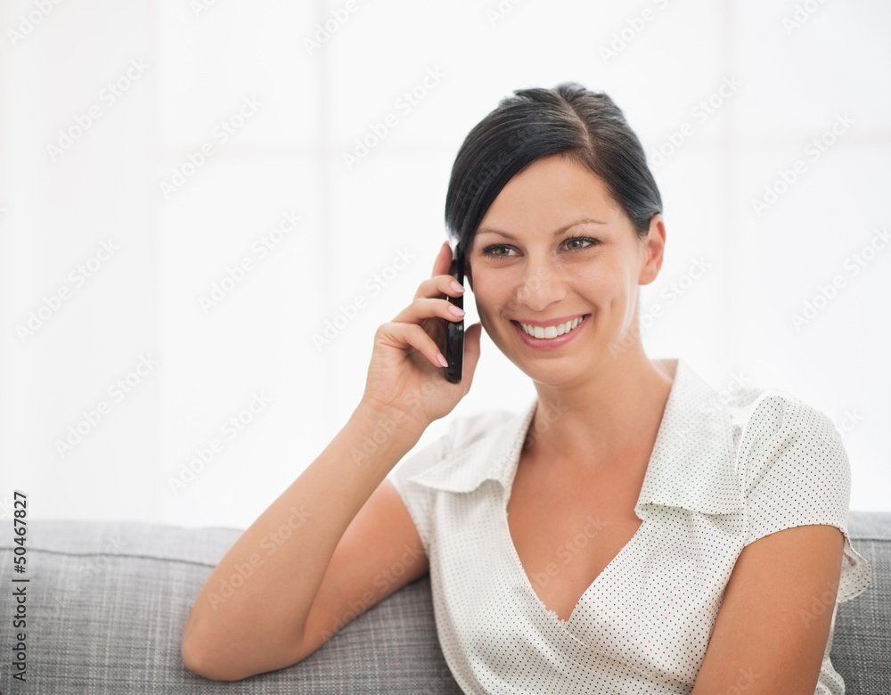 Smiling young woman sitting on couch and talking cell phone Smiling young woman sitting on couch and talking cell phone