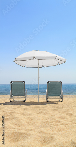 Umbrella and lounge chairs on idyllic beach